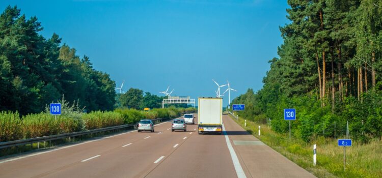 vehicle driving on freeway towards wind turbines